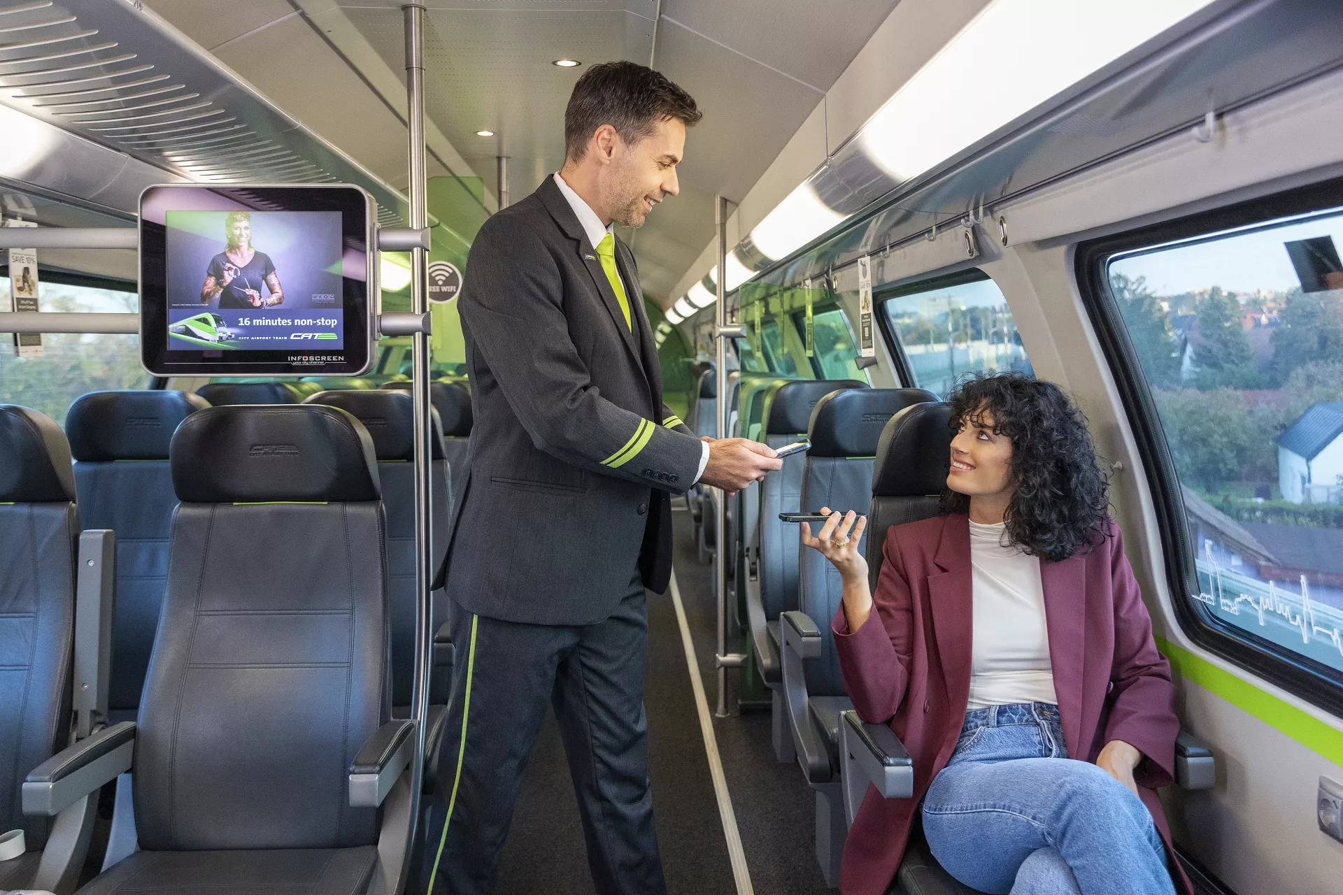 A woman holds up her smartphone with her electronic ticket for inspection while a CAT train attendant checks it